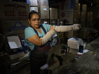 Josefina Aguilar, an industrial biochemist, puts on bandages before making handcrafted balls made of blown glass for sale in the Tlahuac mun...