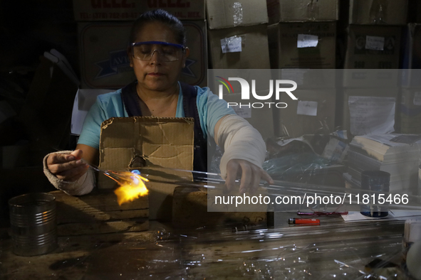 Josefina Aguilar, an industrial biochemist, makes handcrafted balls made of blown glass for sale in the Tlahuac municipality, Mexico City, o...