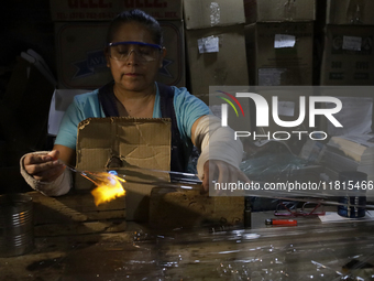 Josefina Aguilar, an industrial biochemist, makes handcrafted balls made of blown glass for sale in the Tlahuac municipality, Mexico City, o...