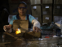 Josefina Aguilar, an industrial biochemist, makes handcrafted balls made of blown glass for sale in the Tlahuac municipality, Mexico City, o...