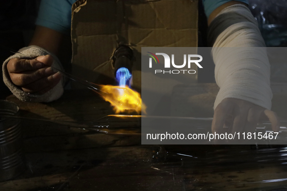 Josefina Aguilar, an industrial biochemist, makes handcrafted balls made of blown glass for sale in the Tlahuac municipality, Mexico City, o...