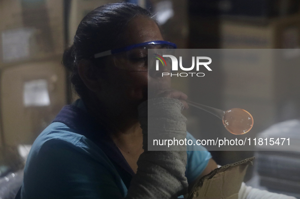 Josefina Aguilar, an industrial biochemist, makes handcrafted balls made of blown glass for sale in the Tlahuac municipality, Mexico City, o...