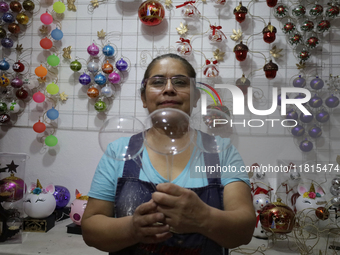 Josefina Aguilar, an industrial biochemist, holds handcrafted balls made of blown glass for sale in the Tlahuac municipality, Mexico City, o...