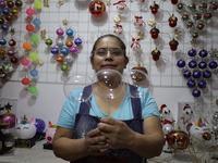 Josefina Aguilar, an industrial biochemist, holds handcrafted balls made of blown glass for sale in the Tlahuac municipality, Mexico City, o...