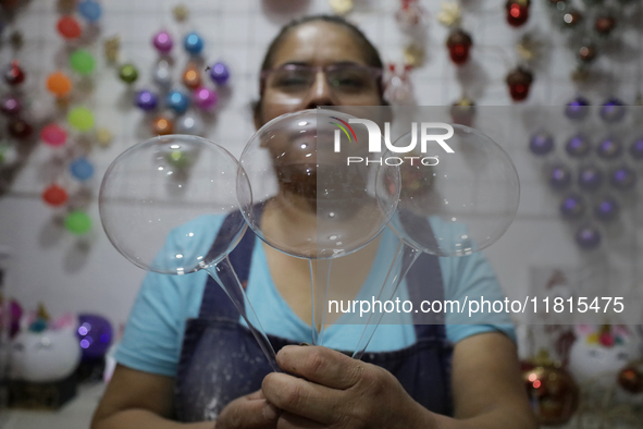 Josefina Aguilar, an industrial biochemist, holds handcrafted balls made of blown glass for sale in the Tlahuac municipality, Mexico City, o...