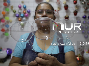 Josefina Aguilar, an industrial biochemist, holds handcrafted balls made of blown glass for sale in the Tlahuac municipality, Mexico City, o...