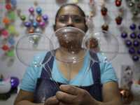 Josefina Aguilar, an industrial biochemist, holds handcrafted balls made of blown glass for sale in the Tlahuac municipality, Mexico City, o...