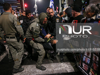 Police officers drag demonstrators as people block a road during a protest in support of the hostages kidnapped during the deadly October 7,...