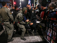 Police officers drag demonstrators as people block a road during a protest in support of the hostages kidnapped during the deadly October 7,...