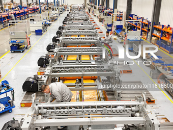 Workers assemble shuttleless looms at a workshop of Qingdao Century Haijia Machinery Co., LTD in Qingdao, China, on November 28, 2024. (