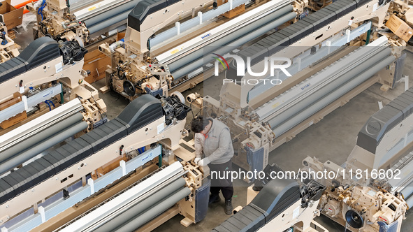 Workers make the final adjustment of a water-jet loom to be exported at the workshop of Qingdao Century Haijia Machinery Co., LTD in Qingdao...