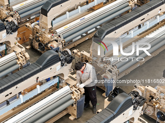 Workers make the final adjustment of a water-jet loom to be exported at the workshop of Qingdao Century Haijia Machinery Co., LTD in Qingdao...