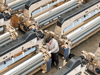 Workers make the final adjustment of a water-jet loom to be exported at the workshop of Qingdao Century Haijia Machinery Co., LTD in Qingdao...