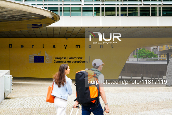 Two people walk in front of the Berlaymont building in Brussels, Belgium, on July 30, 2023. Recognized as the headquarters of the European C...