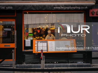 A member of staff is seen at a window of a restaurant in Chinatown, London, on November 28, 2024. (