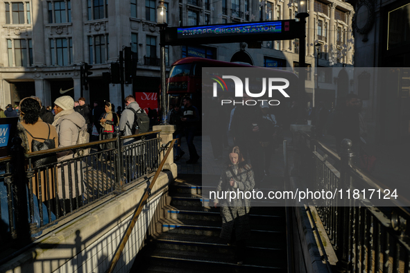 People descend into the Oxford Circus underground station in London, United Kingdom, on November 28, 2024. 