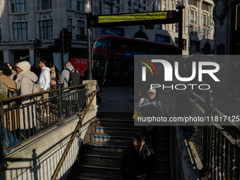 People descend into the Oxford Circus underground station in London, United Kingdom, on November 28, 2024. (