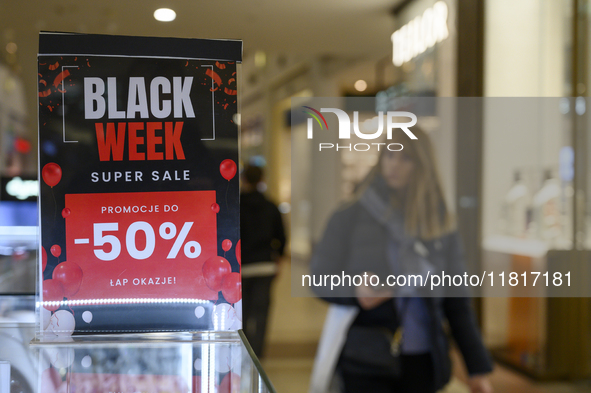 A person walks past a placard that reads ''Black Weeks Super Sales -50%'' ahead of Black Friday in Warsaw, Poland, on November 28, 2024. 