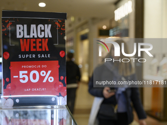 A person walks past a placard that reads ''Black Weeks Super Sales -50%'' ahead of Black Friday in Warsaw, Poland, on November 28, 2024. (