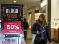 A person walks past a placard that reads ''Black Weeks Super Sales -50%'' ahead of Black Friday in Warsaw, Poland, on November 28, 2024. (