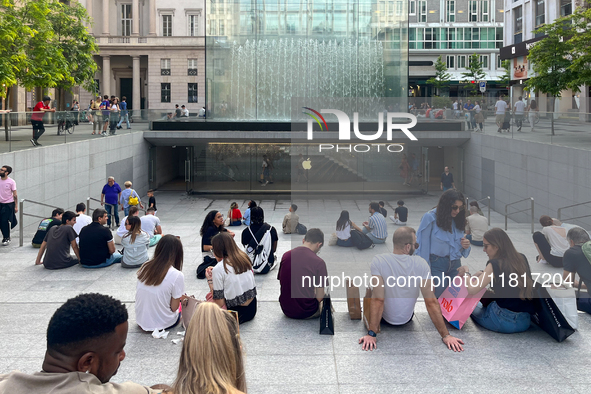 Shoppers and tourists gather outside the Apple Store in Milan, Italy, on May 27, 2023. They relax and socialize at the entrance of the store...