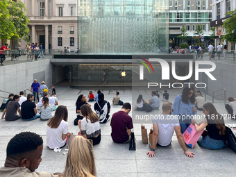 Shoppers and tourists gather outside the Apple Store in Milan, Italy, on May 27, 2023. They relax and socialize at the entrance of the store...