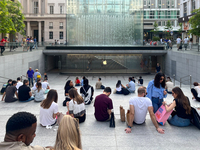 Shoppers and tourists gather outside the Apple Store in Milan, Italy, on May 27, 2023. They relax and socialize at the entrance of the store...