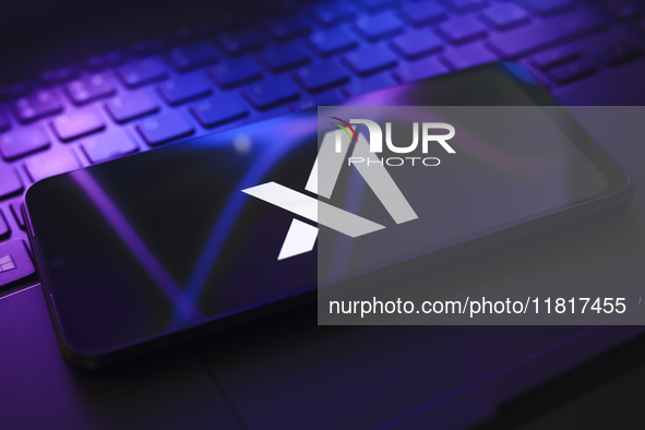 The X.AI Corp. logo appears on the screen of a smartphone that rests on top of the laptop keyboard in Reno, United States, on November 28, 2...