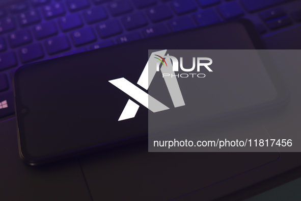 The X.AI Corp. logo appears on the screen of a smartphone that rests on top of the laptop keyboard in Reno, United States, on November 28, 2...