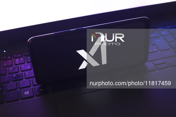 The X.AI Corp. logo appears on the screen of a smartphone that rests on top of the laptop keyboard in Reno, United States, on November 28, 2...