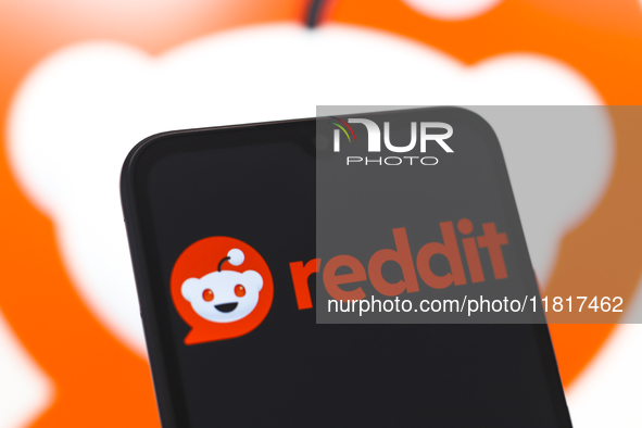 The Reddit logo appears on the screen of a smartphone and in the background on the computer screen in Reno, United States, on November 28, 2...