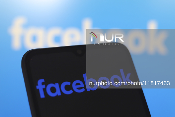 The Facebook logo appears on the screen of a smartphone and in the background on the computer screen in Reno, United States, on November 28,...