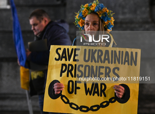 KRAKOW, POLAND - NOVEMBER 28:
A protester wearing a wreath in Ukrainian colors holds a poster reading 'Save Ukrainian Prisoniers of War' on...