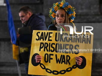 KRAKOW, POLAND - NOVEMBER 28:
A protester wearing a wreath in Ukrainian colors holds a poster reading 'Save Ukrainian Prisoniers of War' on...