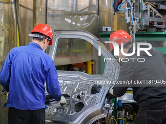 Workers work on the production line at the production workshop of Qingdao Wushun Auto Mold Parts Co., LTD., in West Coast New Area, Qingdao,...