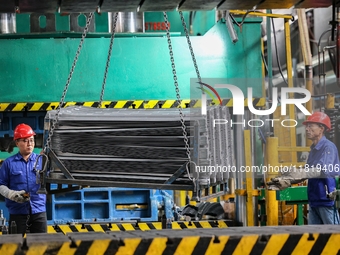 Workers work on the production line at the production workshop of Qingdao Wushun Auto Mold Parts Co., LTD., in West Coast New Area, Qingdao,...