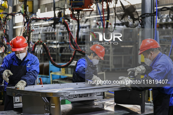 Workers work on the production line at the production workshop of Qingdao Wushun Auto Mold Parts Co., LTD., in West Coast New Area, Qingdao,...