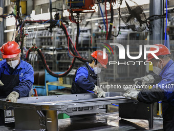 Workers work on the production line at the production workshop of Qingdao Wushun Auto Mold Parts Co., LTD., in West Coast New Area, Qingdao,...