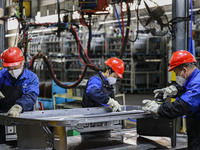 Workers work on the production line at the production workshop of Qingdao Wushun Auto Mold Parts Co., LTD., in West Coast New Area, Qingdao,...