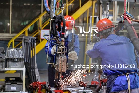 Workers work on the production line at the production workshop of Qingdao Wushun Auto Mold Parts Co., LTD., in West Coast New Area, Qingdao,...