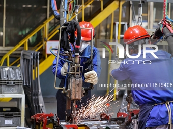 Workers work on the production line at the production workshop of Qingdao Wushun Auto Mold Parts Co., LTD., in West Coast New Area, Qingdao,...