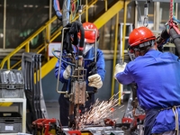 Workers work on the production line at the production workshop of Qingdao Wushun Auto Mold Parts Co., LTD., in West Coast New Area, Qingdao,...