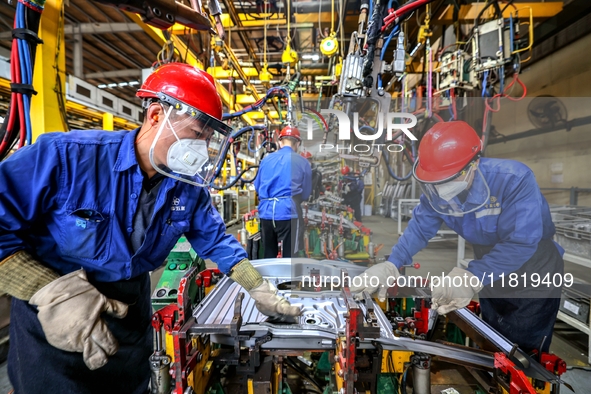 Workers work on the production line at the production workshop of Qingdao Wushun Auto Mold Parts Co., LTD., in West Coast New Area, Qingdao,...