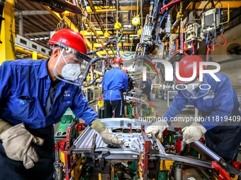 Workers work on the production line at the production workshop of Qingdao Wushun Auto Mold Parts Co., LTD., in West Coast New Area, Qingdao,...