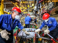 Workers work on the production line at the production workshop of Qingdao Wushun Auto Mold Parts Co., LTD., in West Coast New Area, Qingdao,...