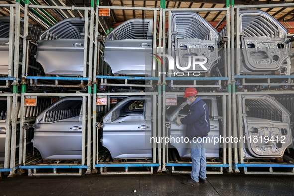 Workers work on the production line at the production workshop of Qingdao Wushun Auto Mold Parts Co., LTD., in West Coast New Area, Qingdao,...