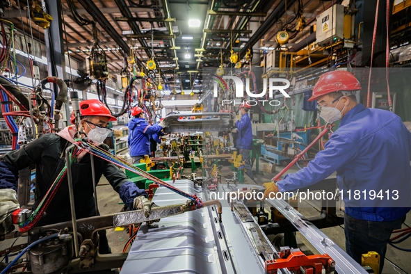 Workers work on the production line at the production workshop of Qingdao Wushun Auto Mold Parts Co., LTD., in West Coast New Area, Qingdao,...