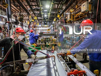 Workers work on the production line at the production workshop of Qingdao Wushun Auto Mold Parts Co., LTD., in West Coast New Area, Qingdao,...