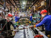 Workers work on the production line at the production workshop of Qingdao Wushun Auto Mold Parts Co., LTD., in West Coast New Area, Qingdao,...