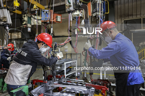 Workers work on the production line at the production workshop of Qingdao Wushun Auto Mold Parts Co., LTD., in West Coast New Area, Qingdao,...